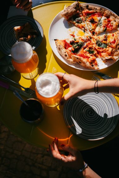Pizza Nduja und zwei frische Pale Ale auf dem Tisch in der Sonne